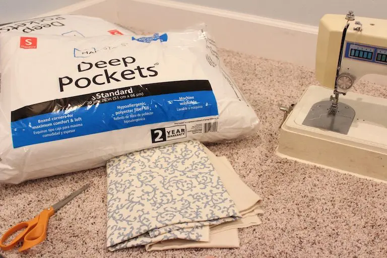 DIY supplies laid out: sewing machine, scissors, and patterned fabric for making a pillow.