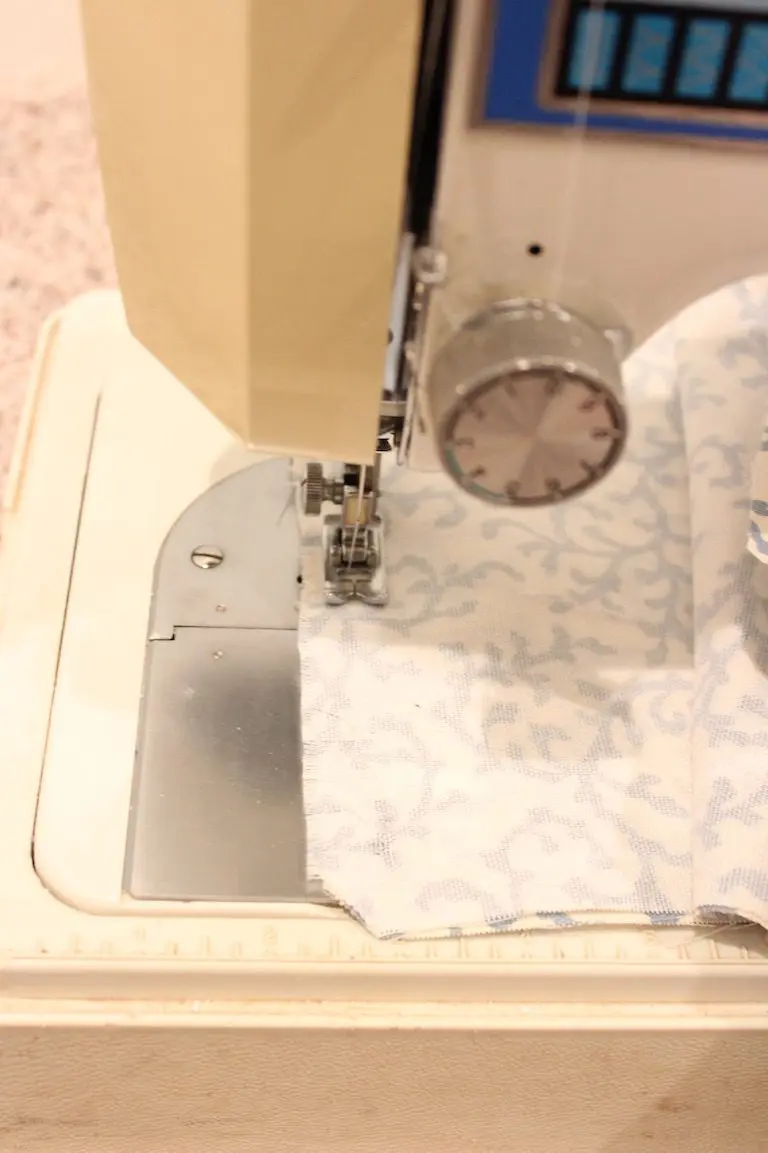 Sewing machine stitching along the edge of patterned fabric for a pillow cover.