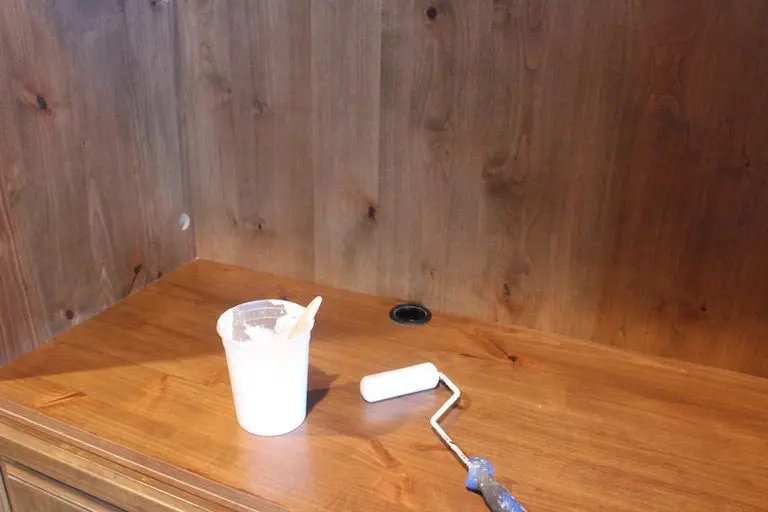 paint roller and a cup of paint on a table