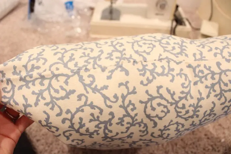 Finished handmade throw pillow with blue patterned fabric on a couch.