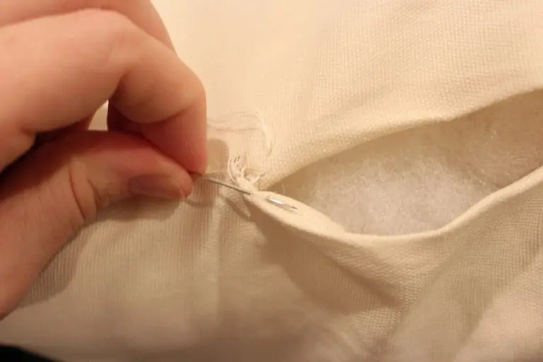 Thread being pulled through fabric fold while sewing a cushion seam.