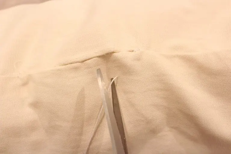 Hand sewing the last section of a pillow seam with neat stitches.