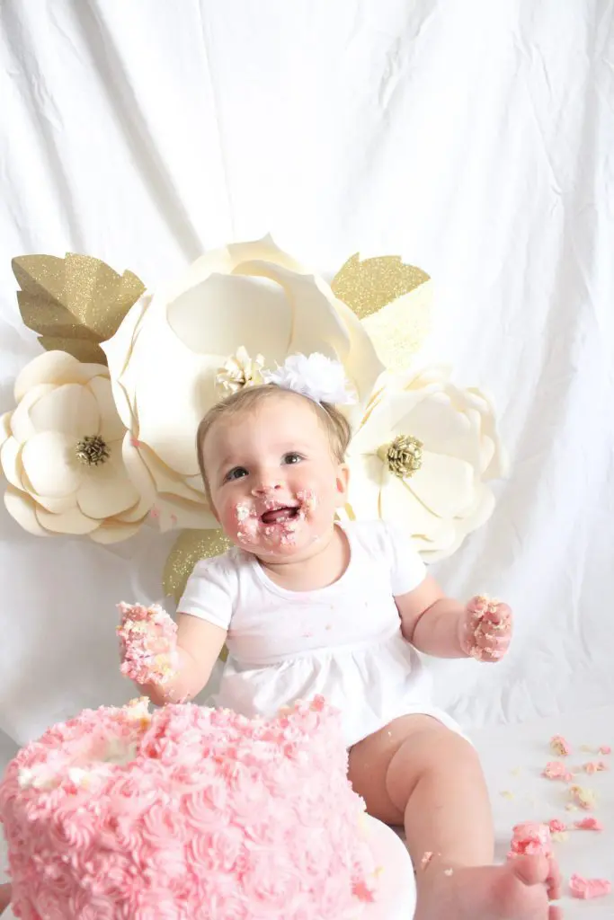 Baby with a pink cake in front of her