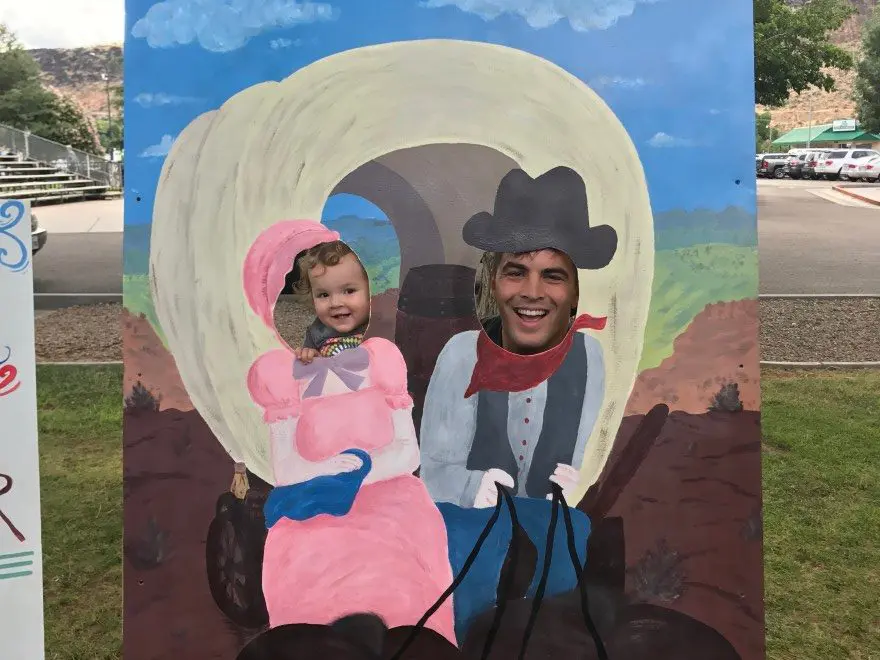 A man and a child with their head poking out of a pioneer day painting