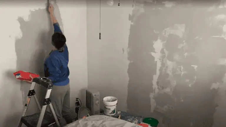 Woman fixing a bedroom wall with joint compound