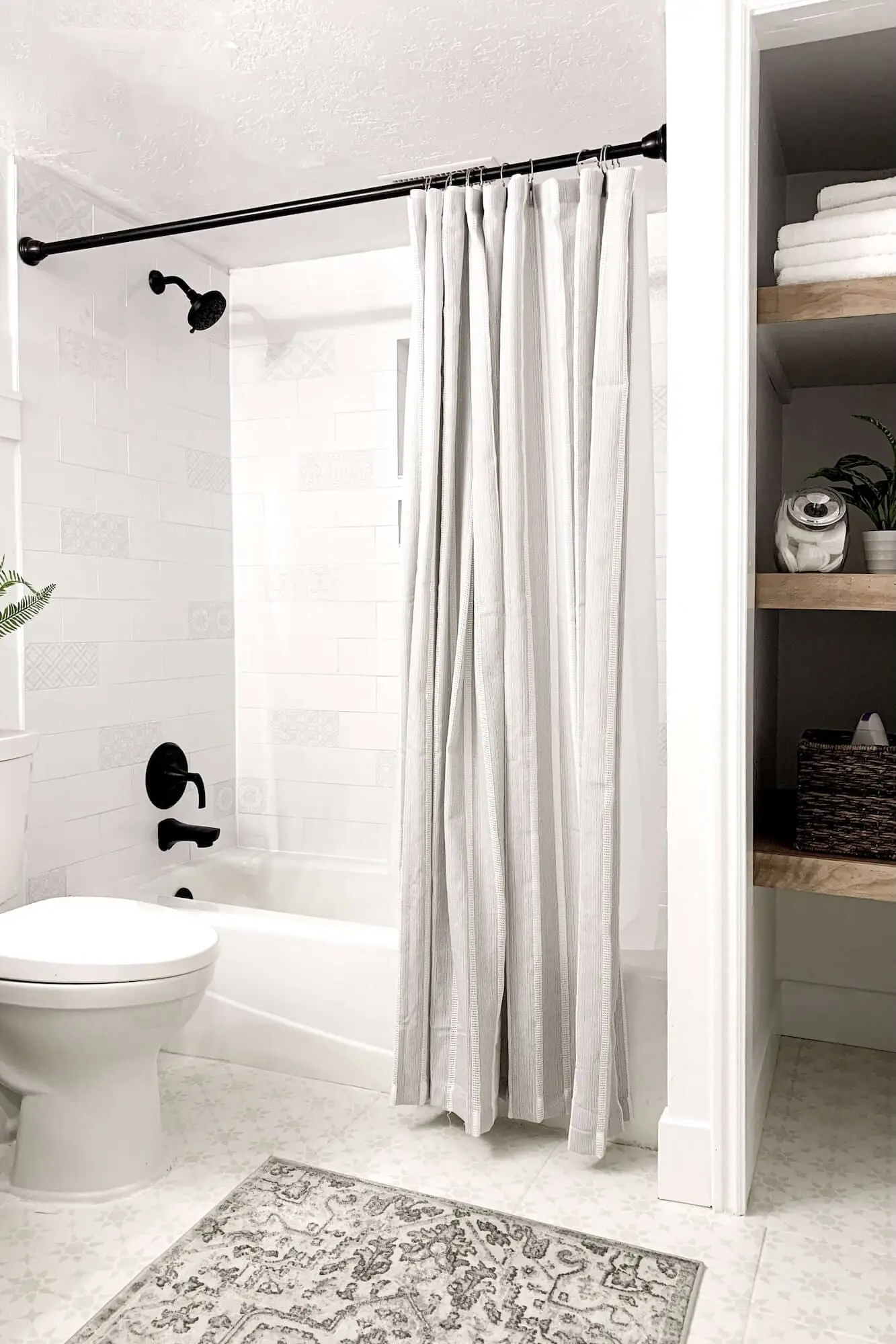 Modern white tile bathroom with painted floor and updated fixtures after mold removal and remodel.
