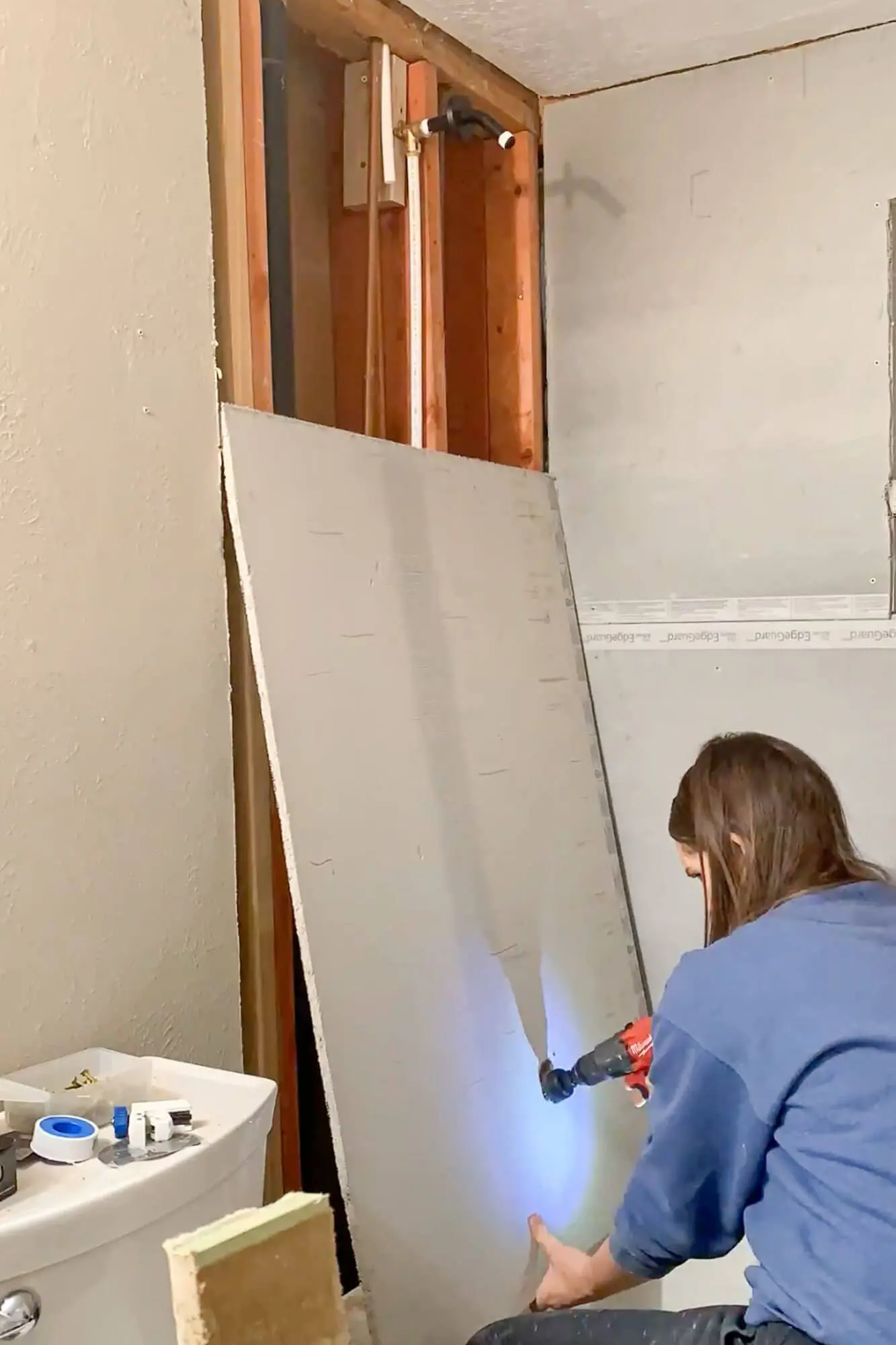 Cutting a plumbing opening into cement board for shower rebuild.