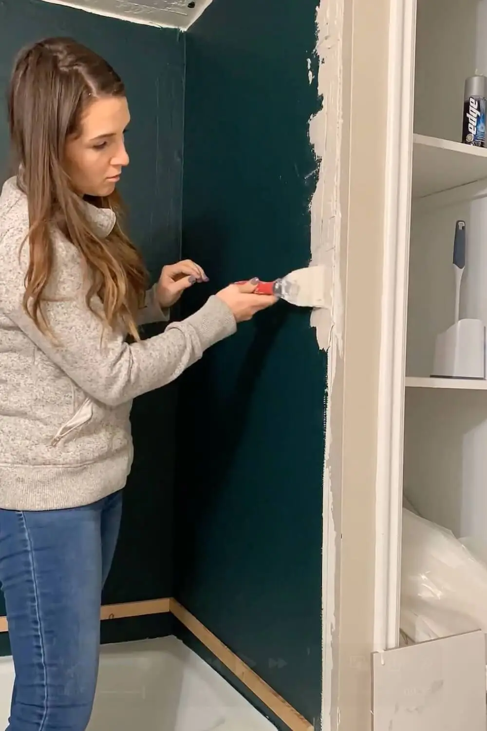 Applying thinset mortar along shower wall edge before tiling.