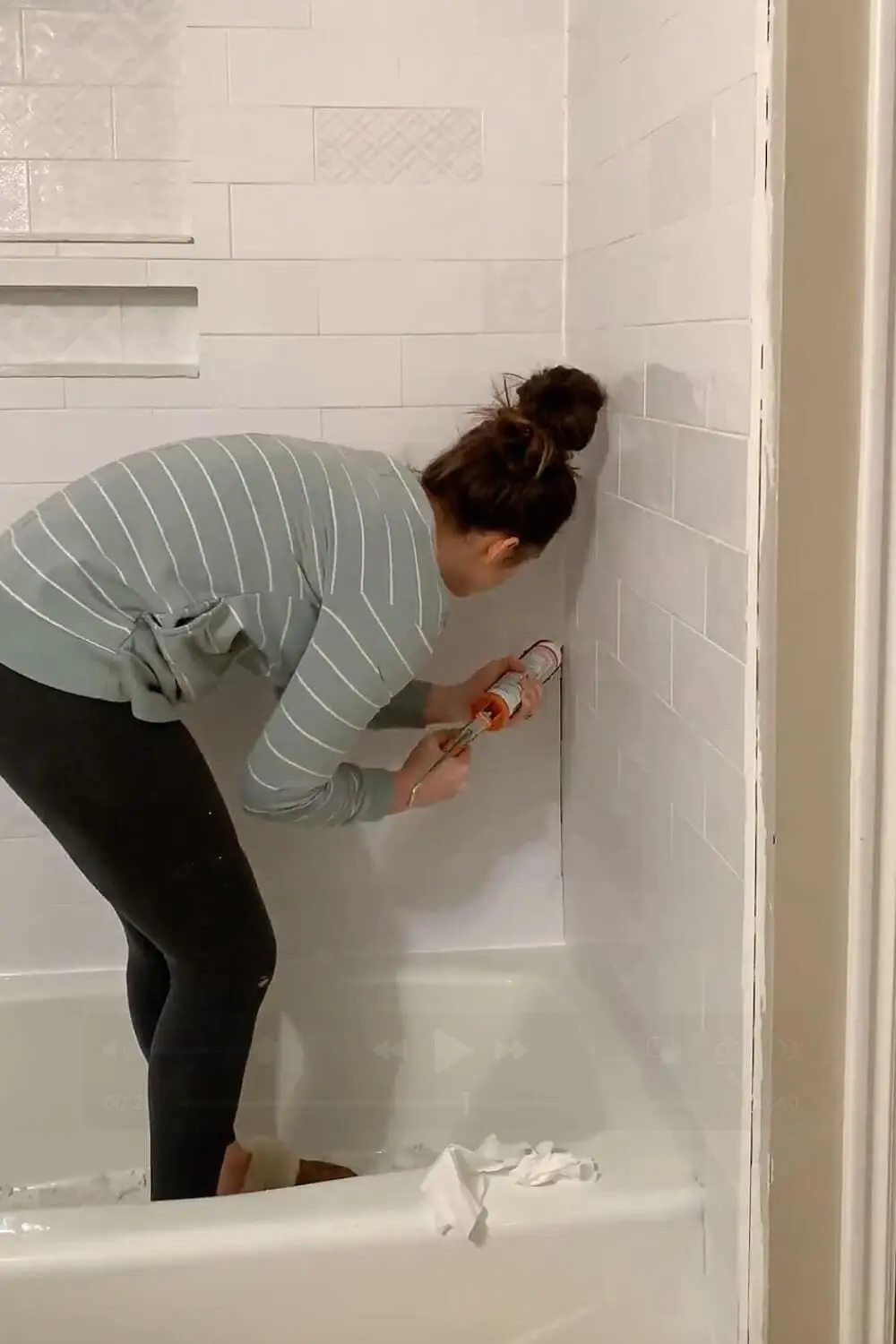 Caulking inside corner of tiled shower wall.
