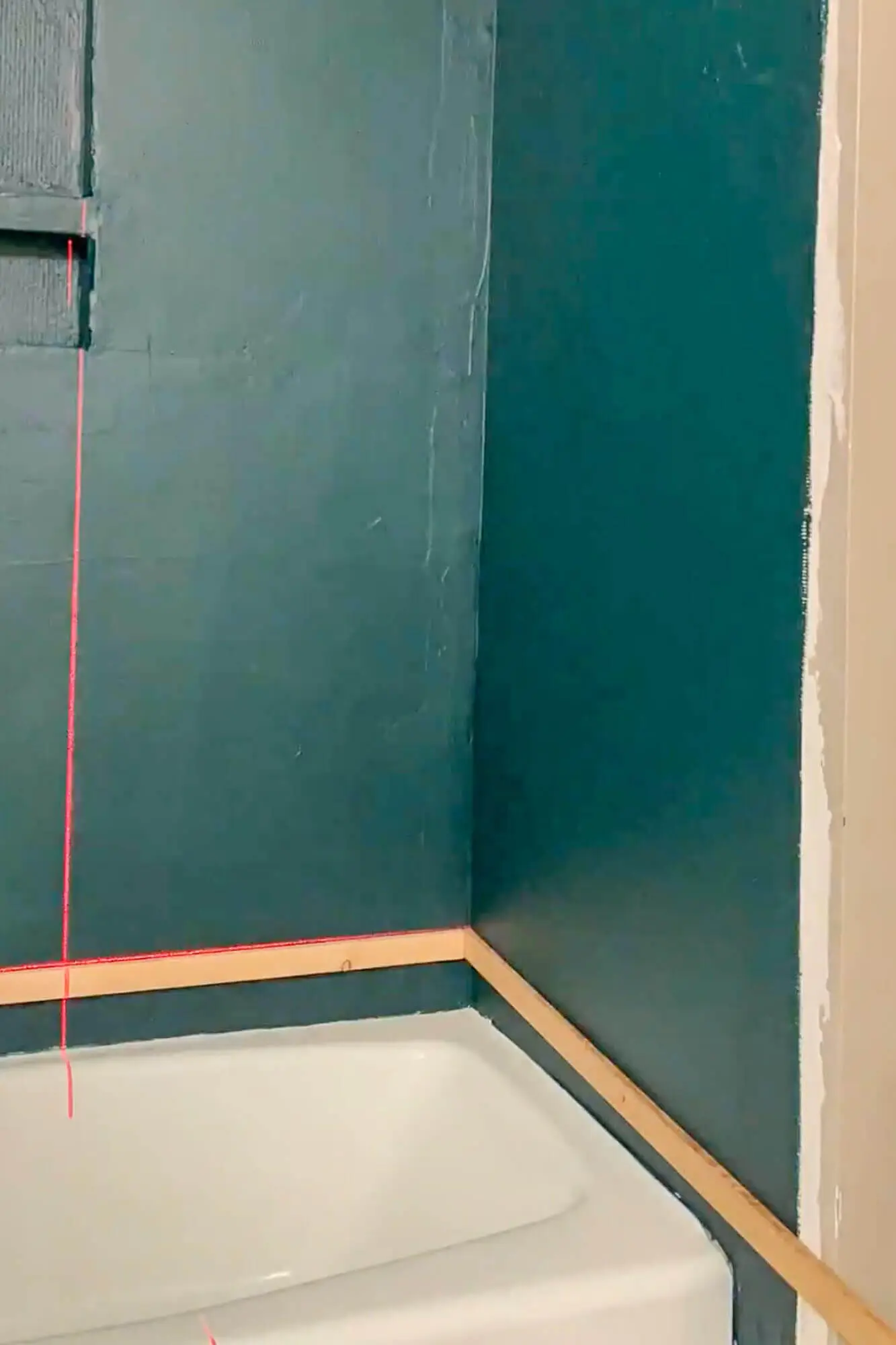 Close-up of ledger board aligned with laser level for tiling.