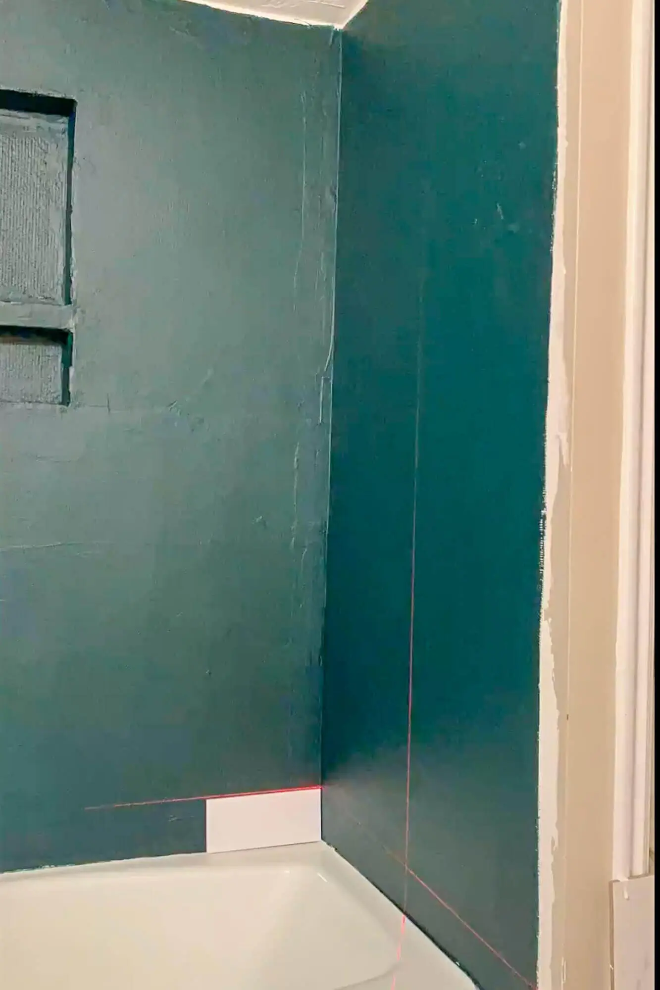 Laser level line on shower wall above tub for first tile row.