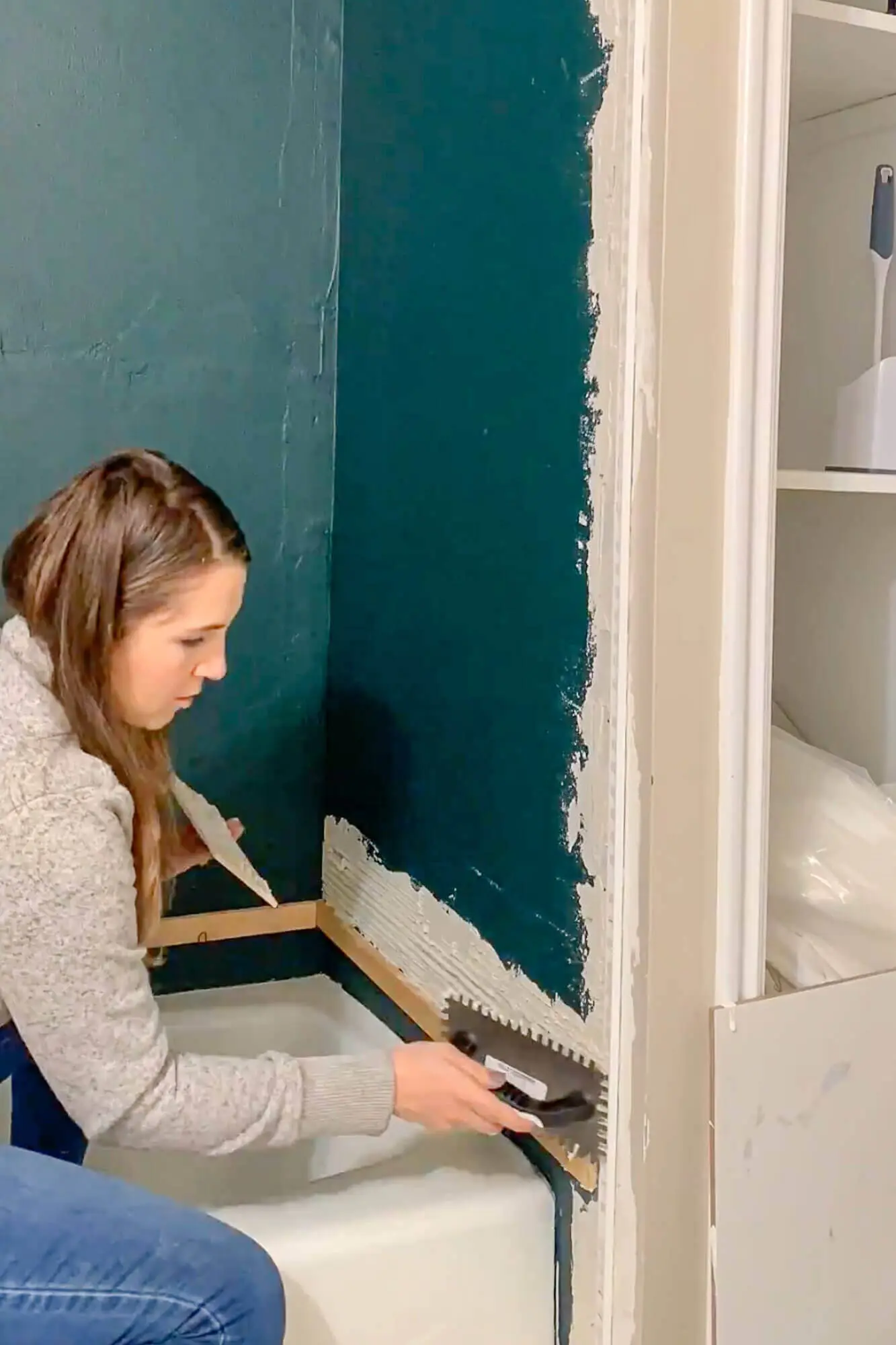 Pressing subway tiles into thinset on shower wall.
