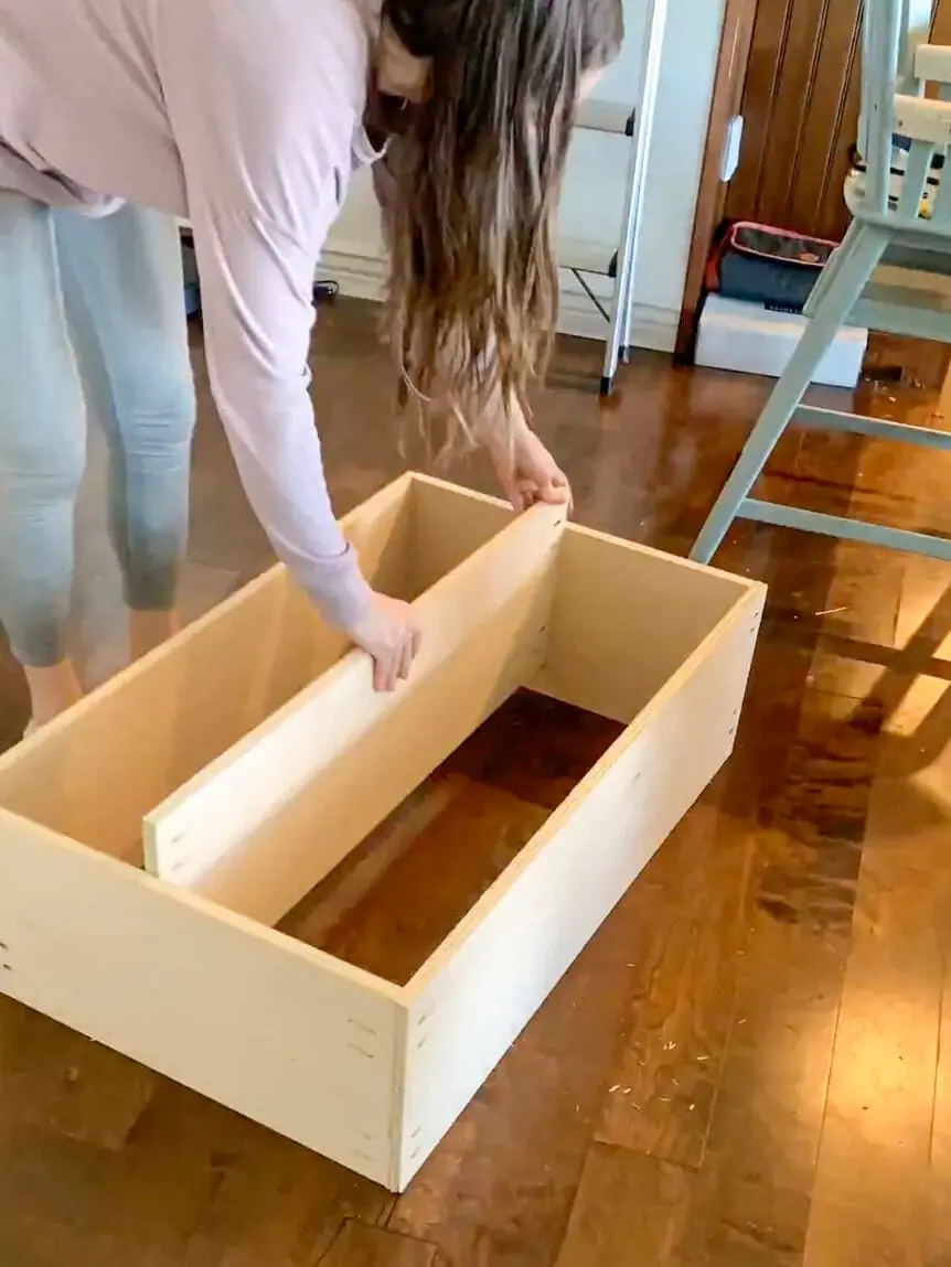 Woman assembling a cabinet with a showcasing a DIY office project.
