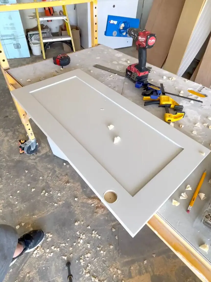 DIY shaker-style cabinet door on a workbench with a power drill and clamps.