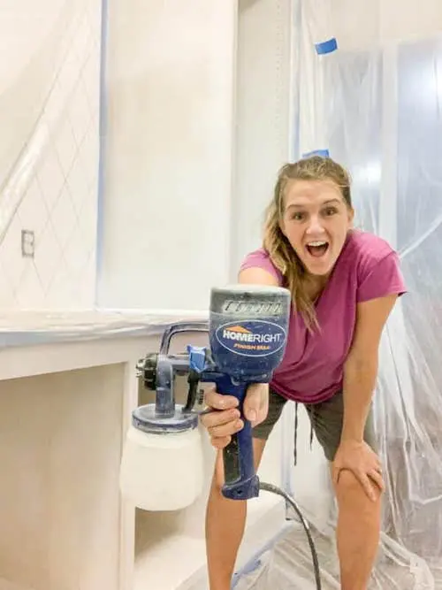 A woman holding a graco paint sprayer