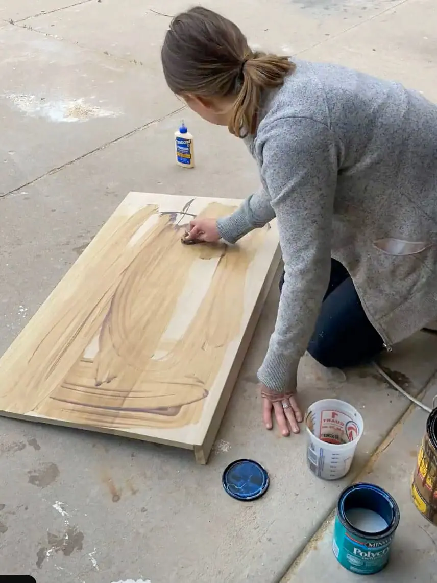 Woman applying wood stain to a DIY office desk for a built-in setup