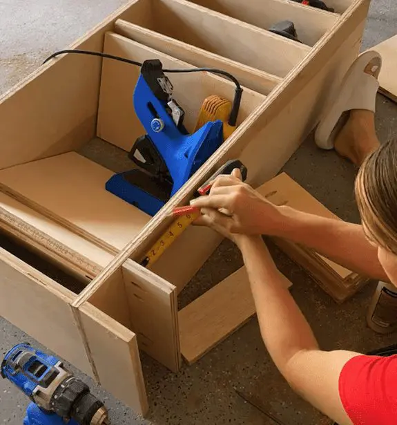 A woman using a measuring tape to measure some wood