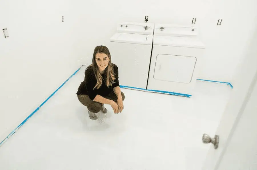 Woman crouching in laundry room on white painted tile