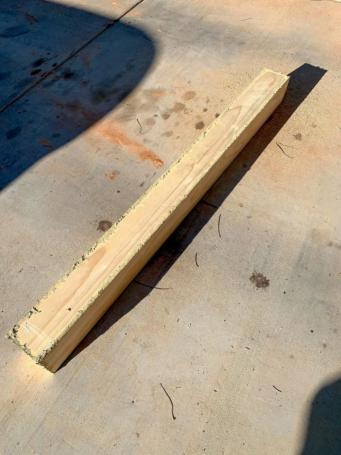 Close-up of wood filler applied along mitered edge of pine board for mantel assembly