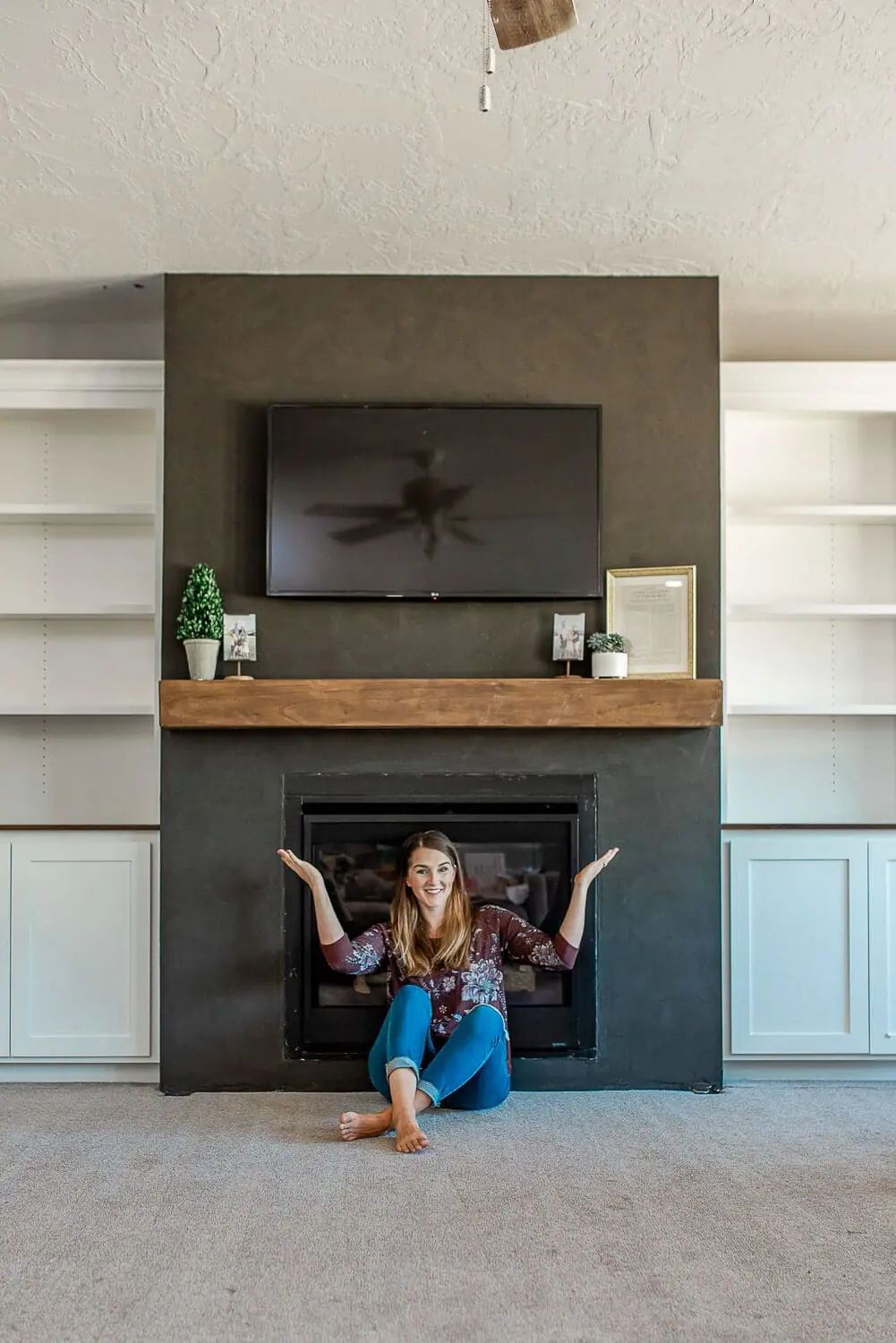Wide view of completed fireplace with floating mantel and symmetrical white built-ins