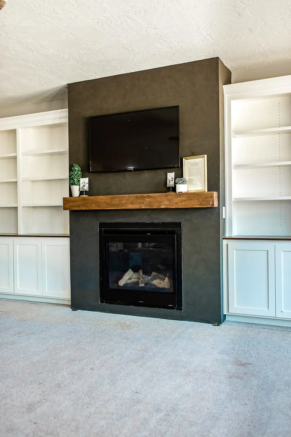 Black Roman Clay fireplace surround with installed wood beam mantel