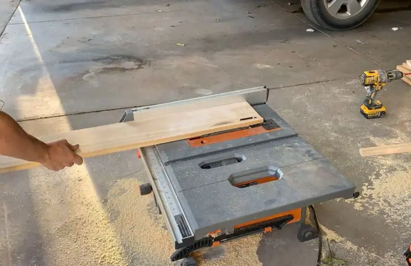 Woman using table saw to cut 45 degree mitered edges on pine boards