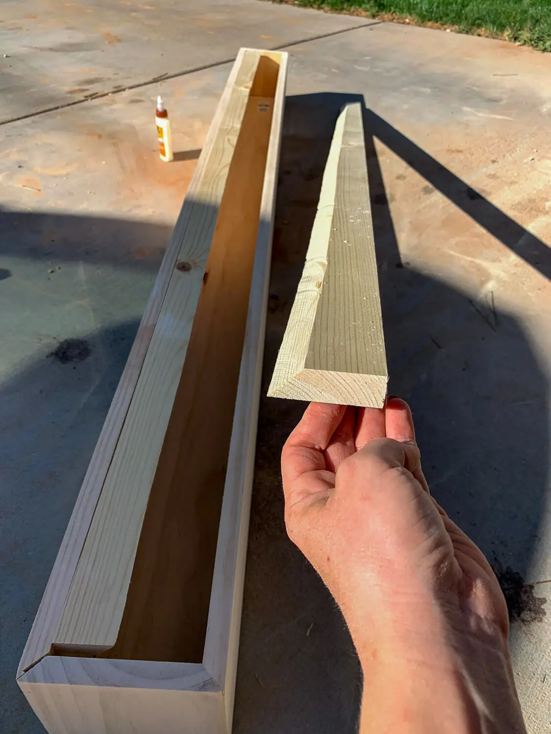 Hand holding French cleat showing 45-degree angled cut for hanging system