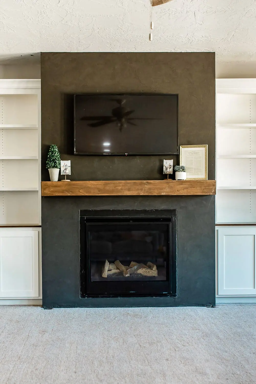 Modern living room with black fireplace and floating wood mantel with TV above