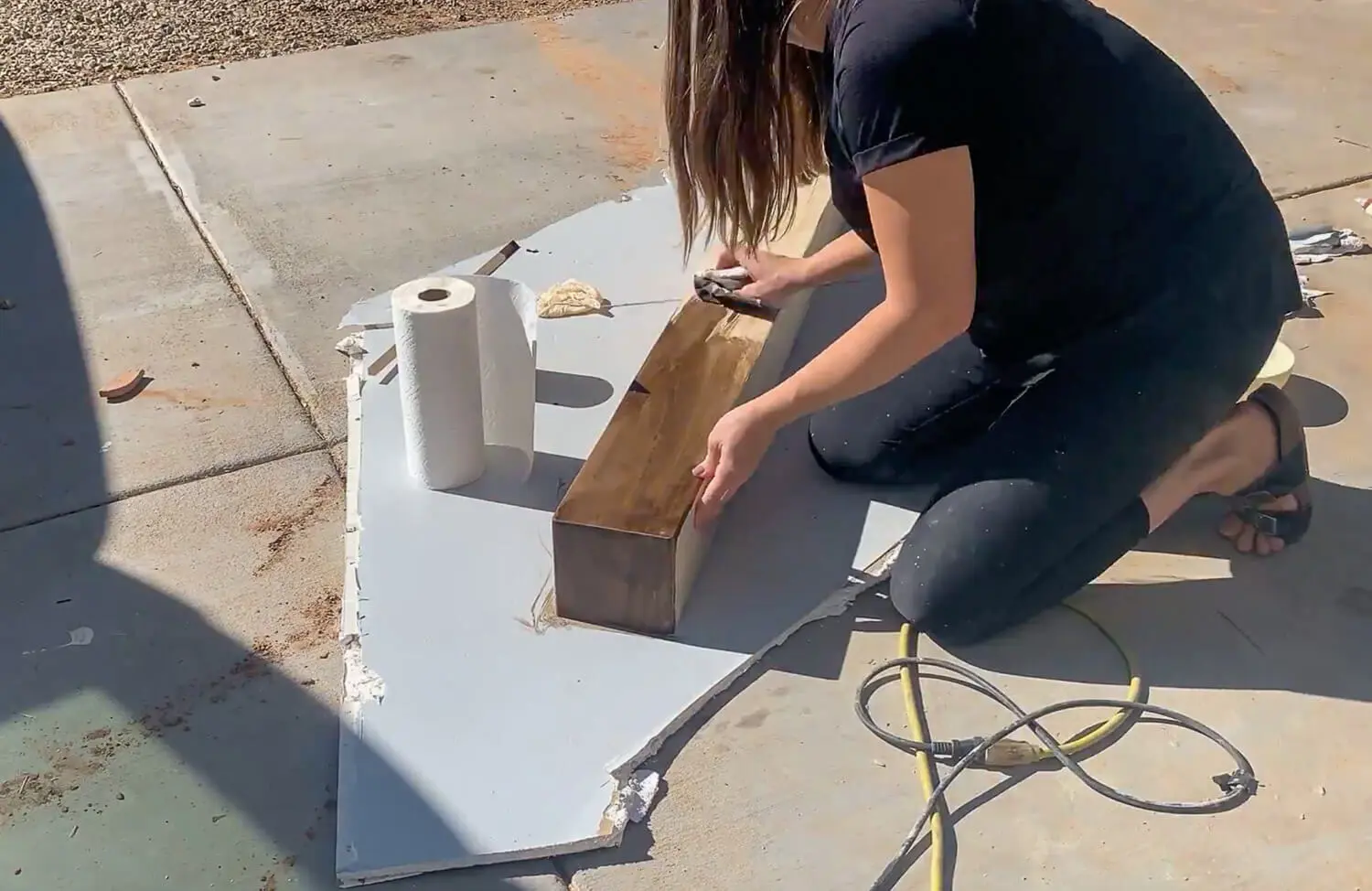 Hand applying stain to raw pine mantel board with brush