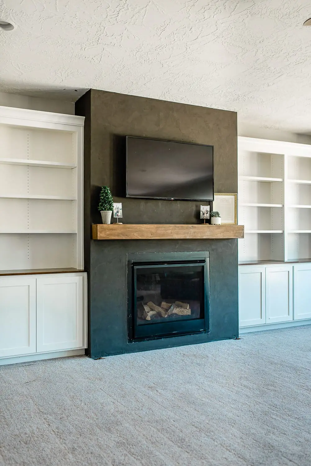 Completed fireplace wall with floating mantel, TV, and white built-in bookcases