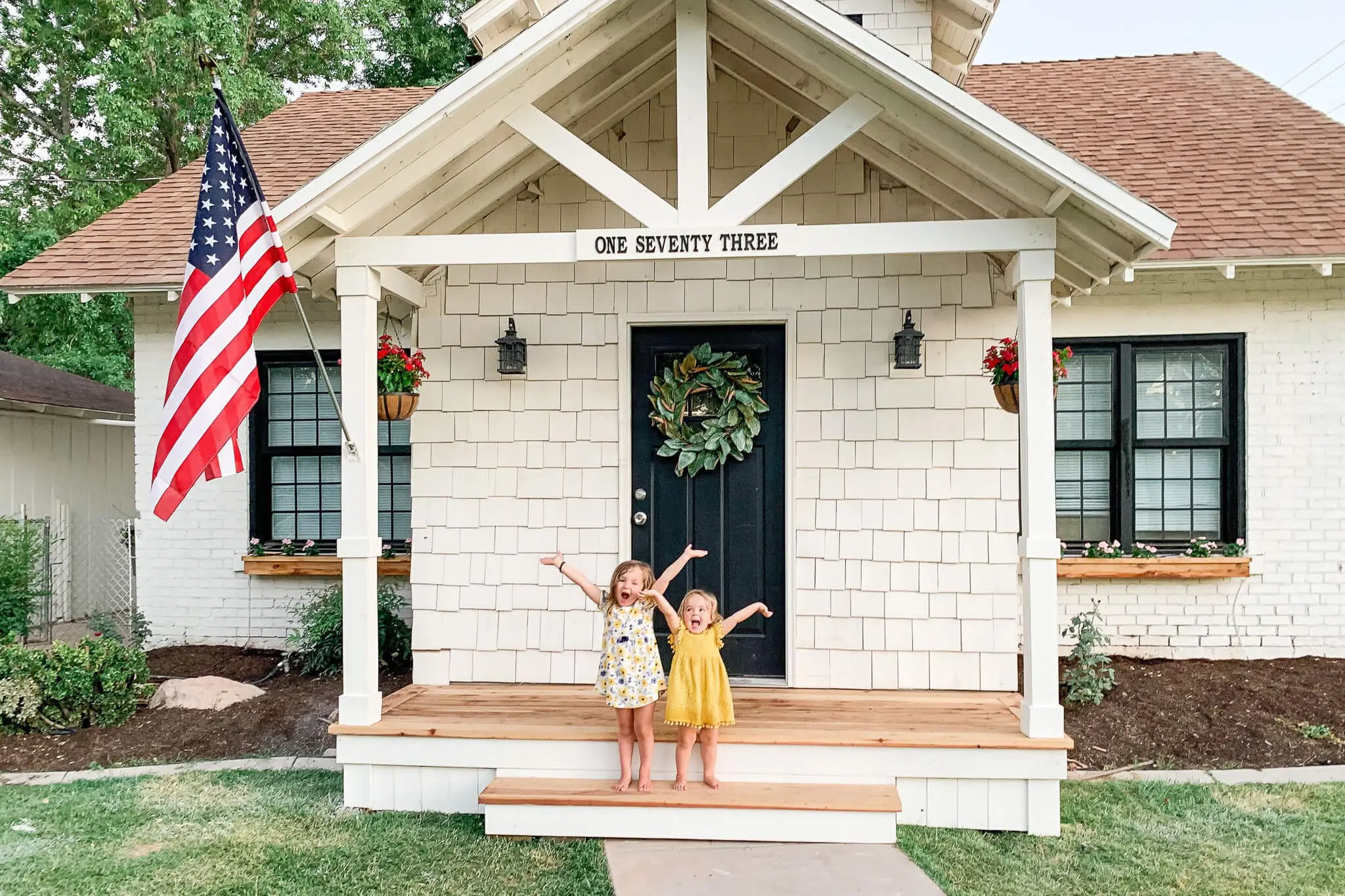 Full view of white front porch on cottage-style home with fresh landscaping and new wood decking.