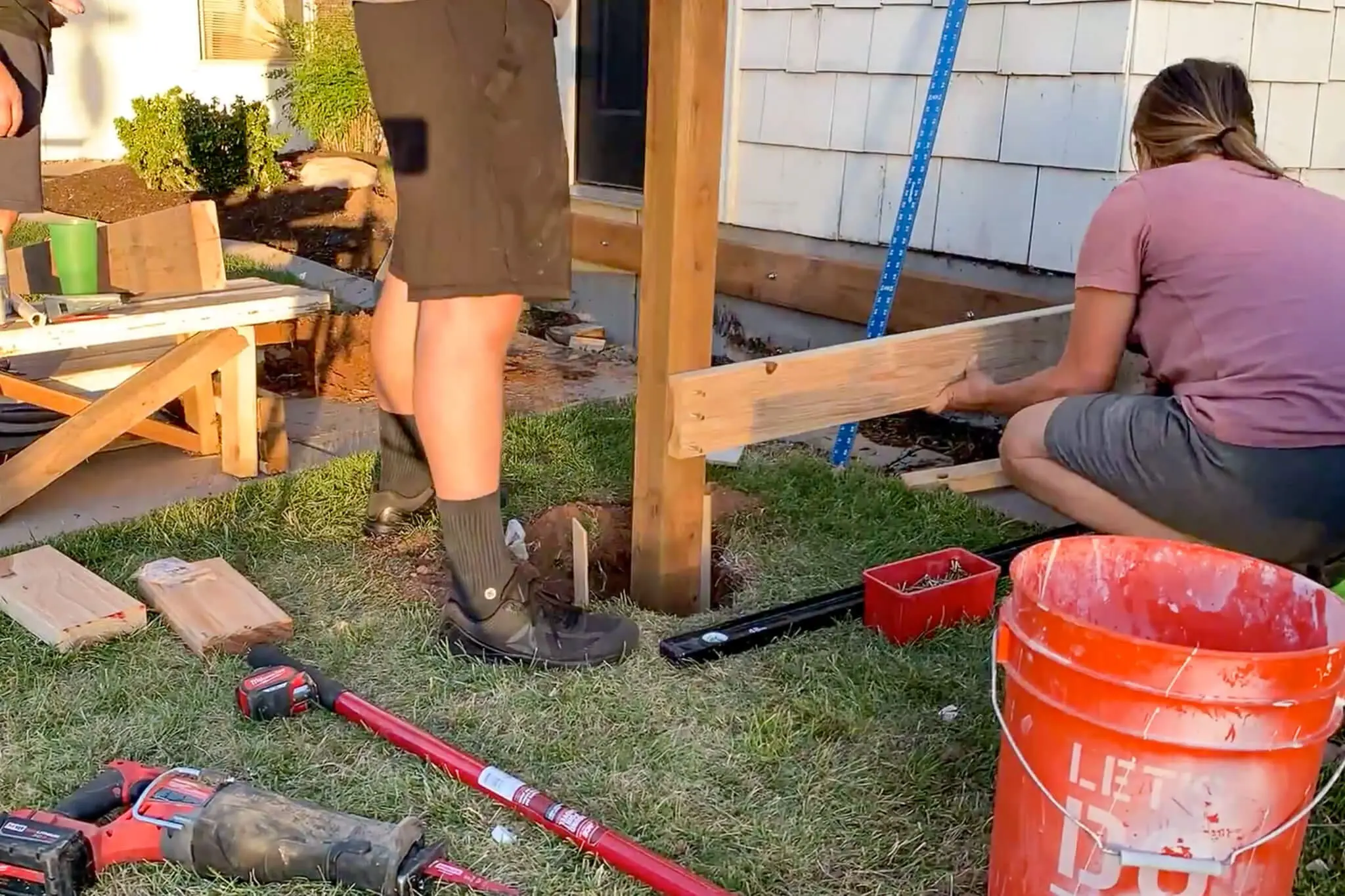 Woman attaching rim joist to deck post while building DIY front porch frame