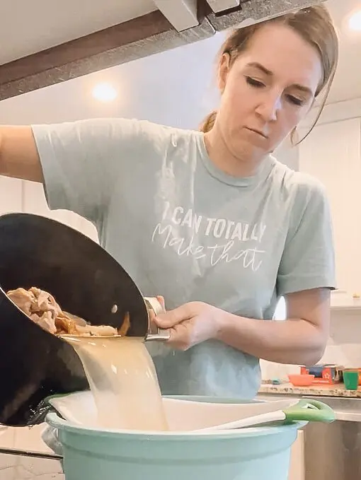 woman straining bone broth