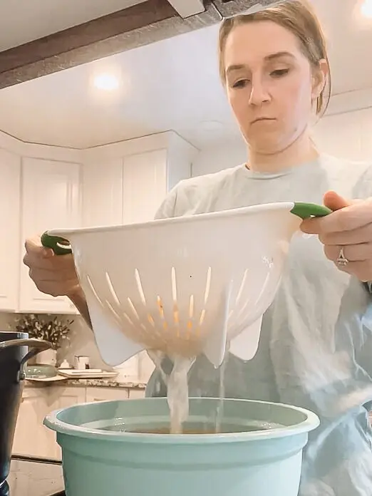 woman straining bone broth