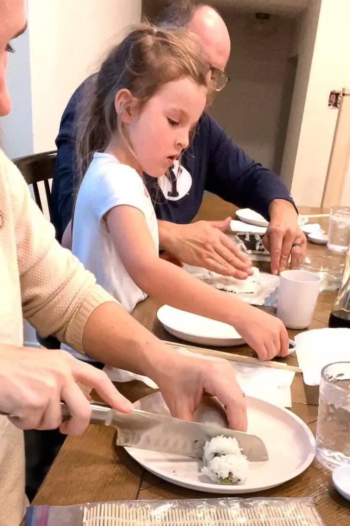 woman using sushi knife to cut up sushi roll