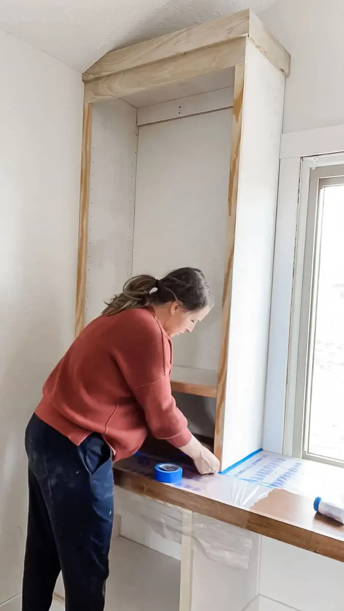 Woman taping off cabinets 