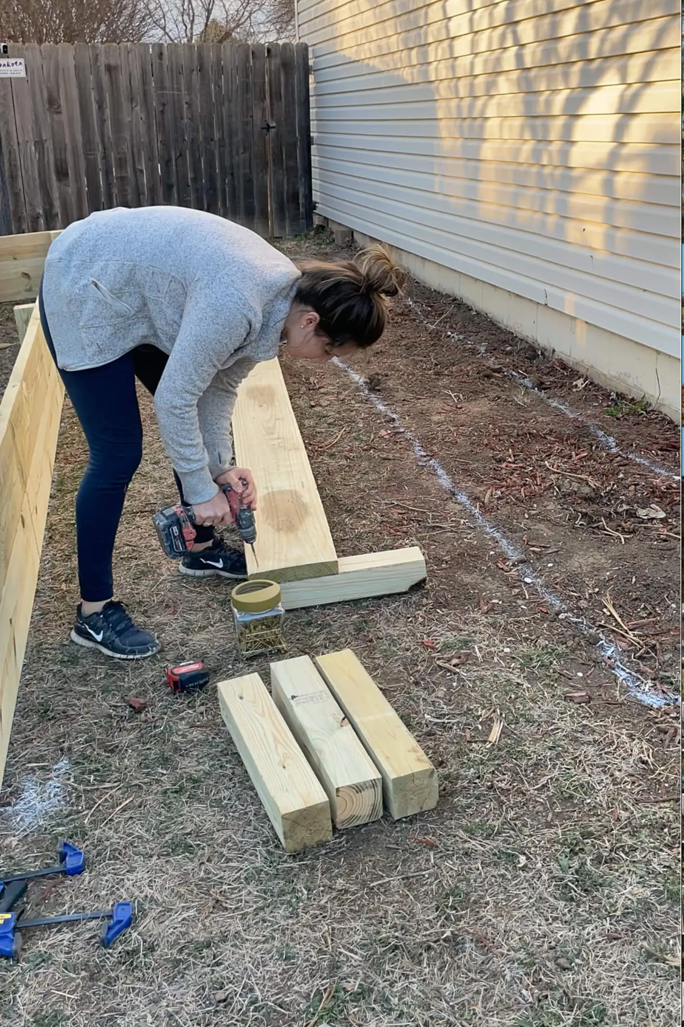 Side view of a southwest-facing yard prepped for raised garden beds, with soil leveled and surrounding vegetation cleared.