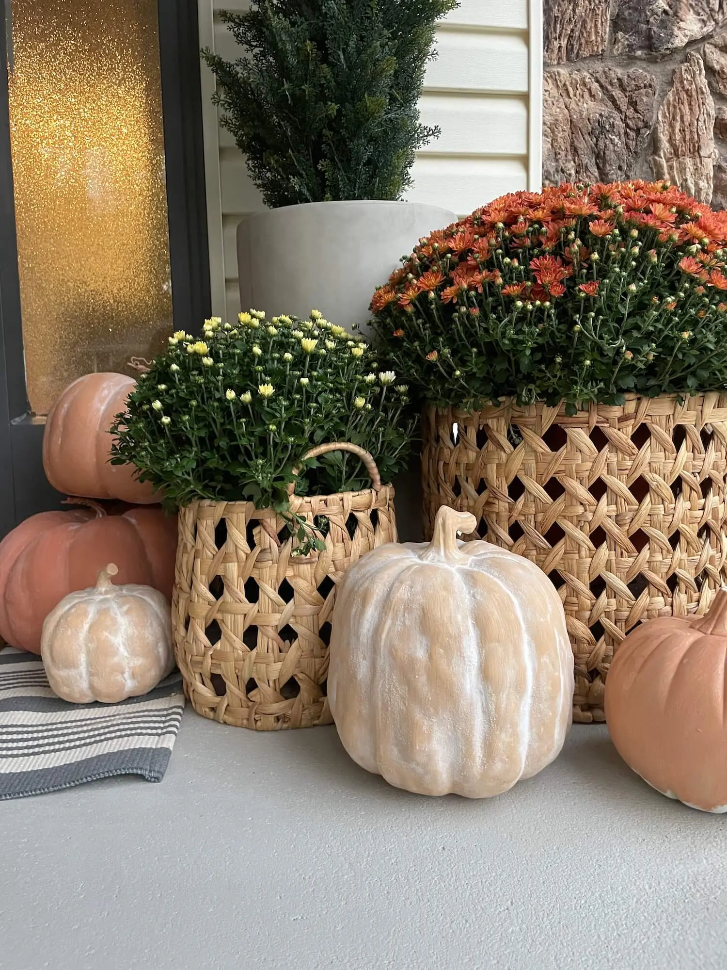 Front porch decorated with rustic faux terracotta pumpkins styled with mums and concrete planters.