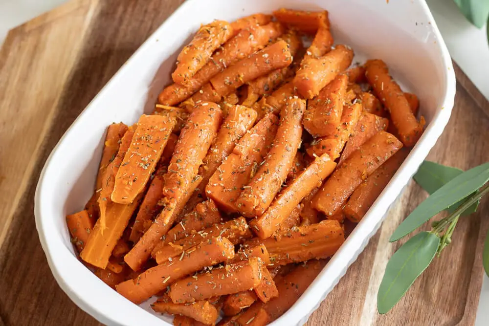 A white dish filled with seasoned steamed carrots, ready to serve as a side dish for Thanksgiving.