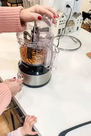 A food processor filled with pretzels, being used to crush them for the raspberry pretzel pie crust.