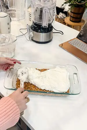 A creamy layer being spread over the baked pretzel crust in preparation for the raspberry pretzel pie.