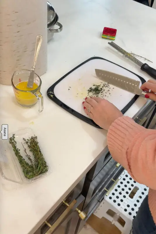 Chopping fresh herbs on a cutting board to be added to the turkey for extra flavor and moisture.