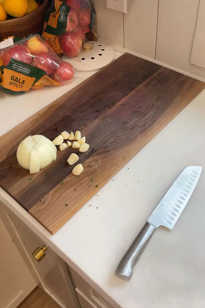 Onion and garlic cloves freshly chopped on a wooden cutting board, prepared to be added to the super moist and tender turkey.