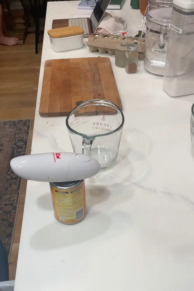 A can of pumpkin puree with an electric can opener on top, ready for use in baking pumpkin cake.