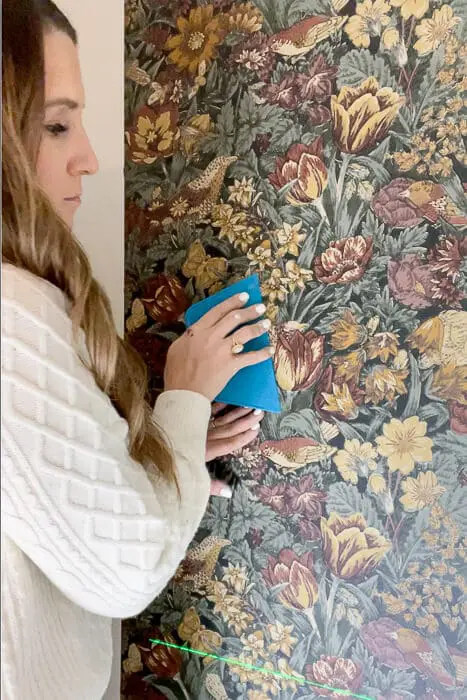 woman flattening wallpaper