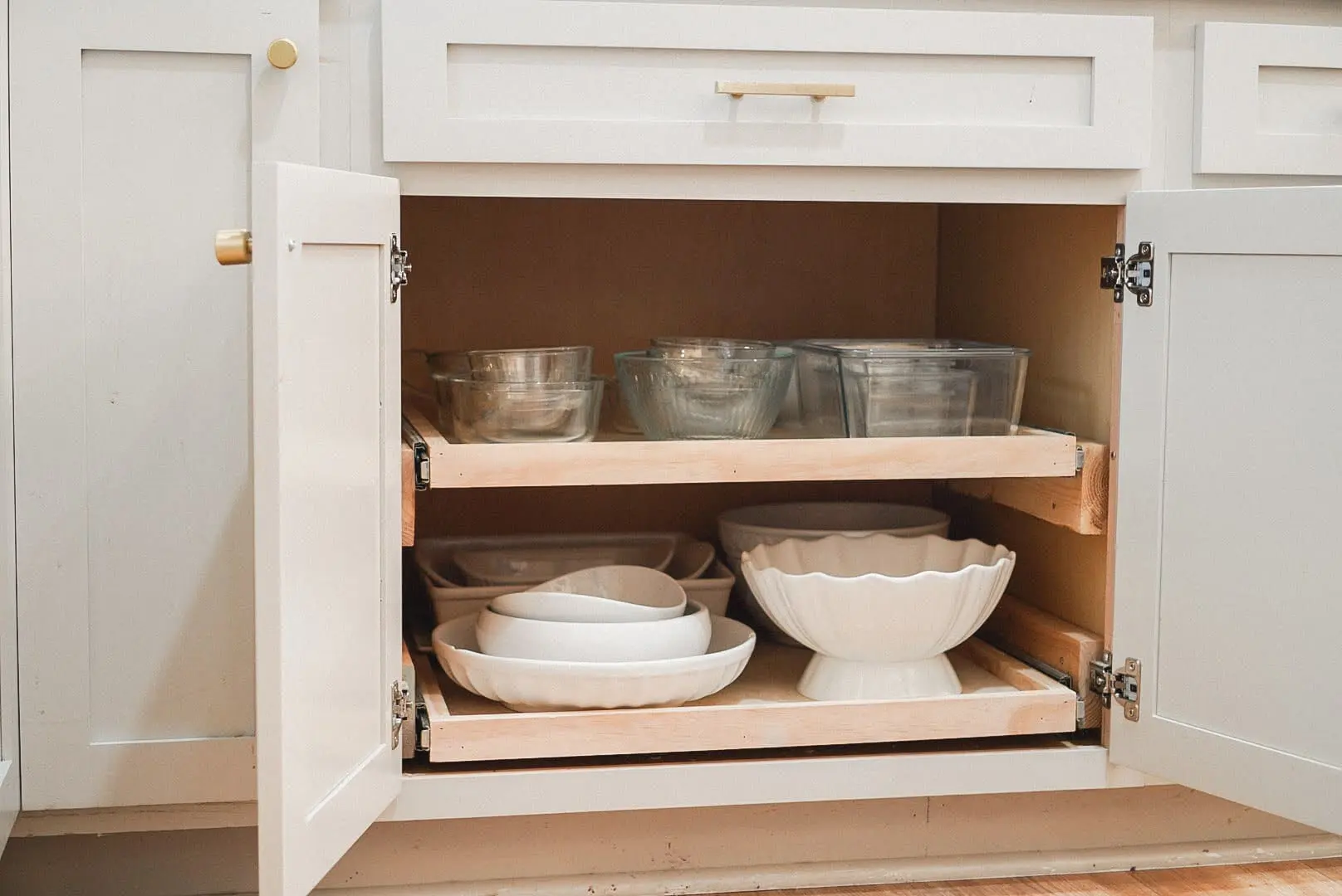 DIY pull-out shelves installed in a kitchen cabinet, providing easy access to dishes and maximizing storage space with a custom-built sliding design.