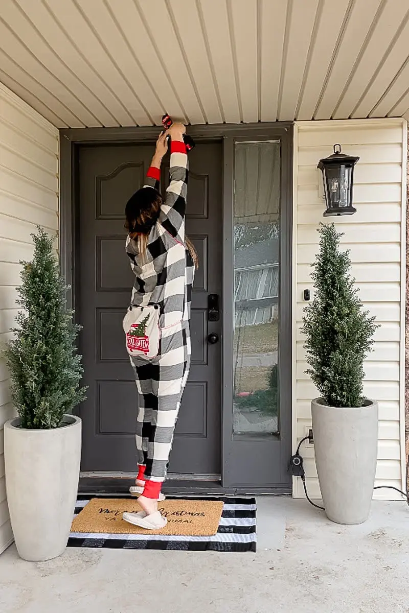 Woman drilling hole in door frame to install Christmas garland