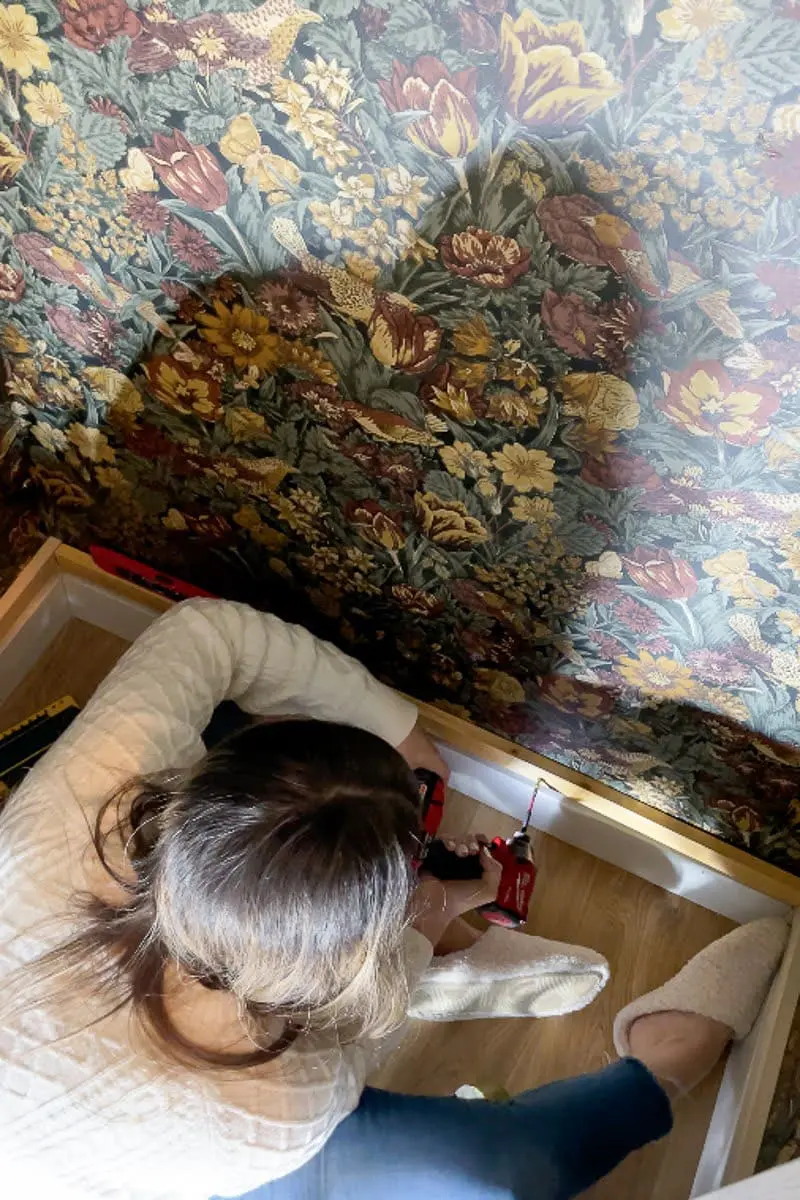 Lady drilling holes into cleat for coat closet makeover shoe shelf