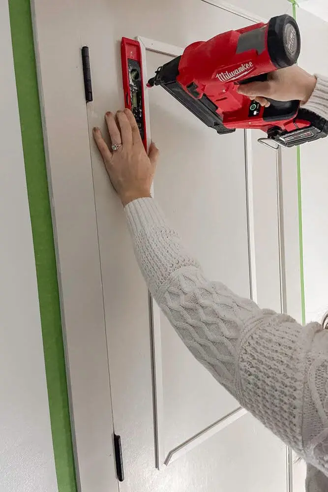 making sure all trim pieces are level while using a brad nailer to nail trim pieces in on door
