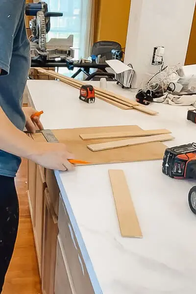Person measuring wooden dividers for a DIY drawer organization project.